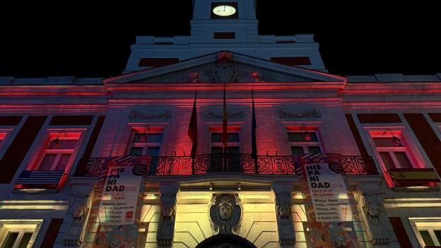 La Comunidad de Madrid ilumina la Real Casa de Correos con los colores de la bandera de España para conmemorar la Fiesta Nacional
